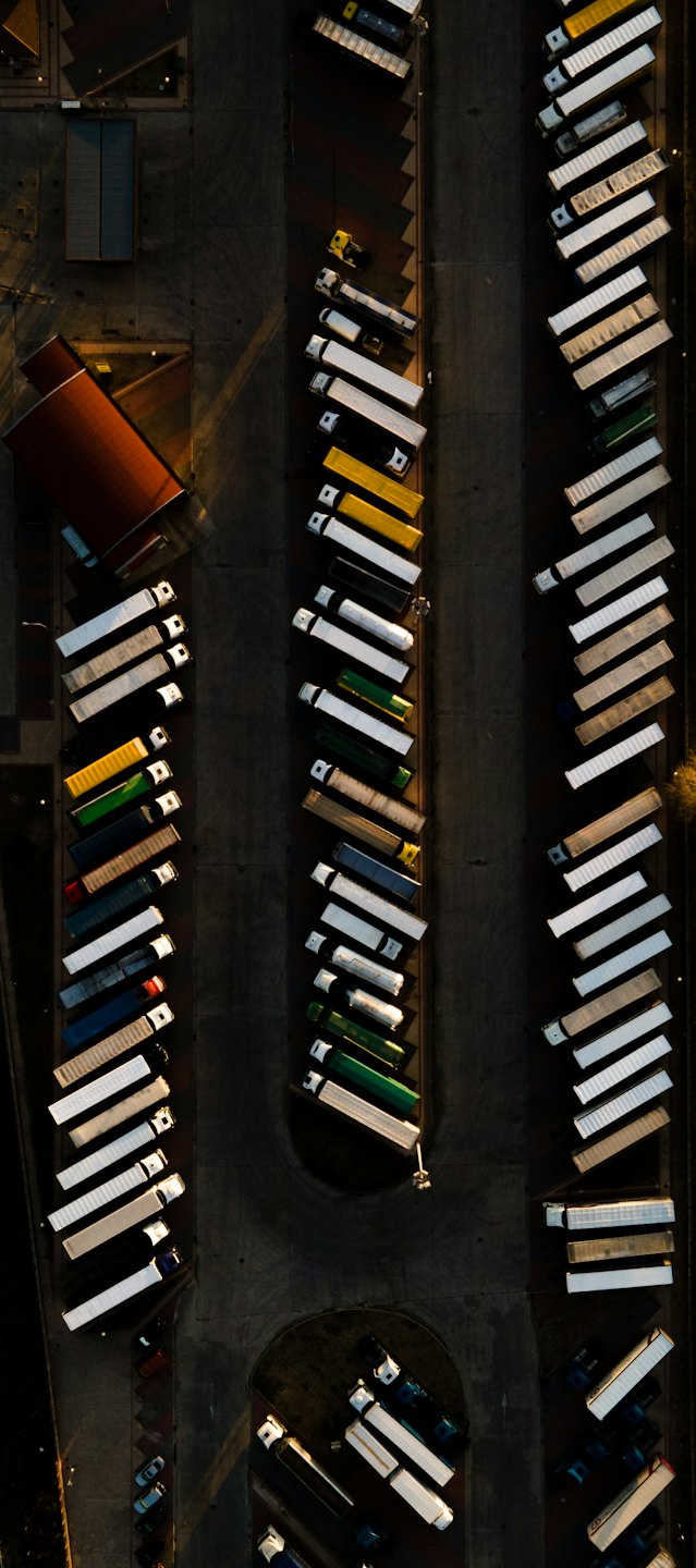 Semi-trucks parked in neat rows at a logistics hub.