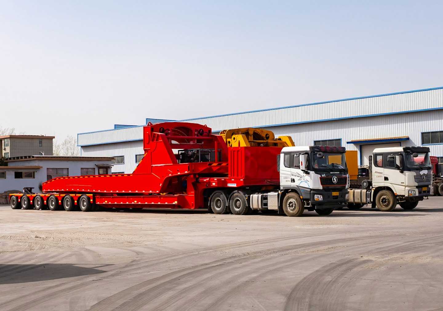 A red semi-truck parked in a large industrial lot.
