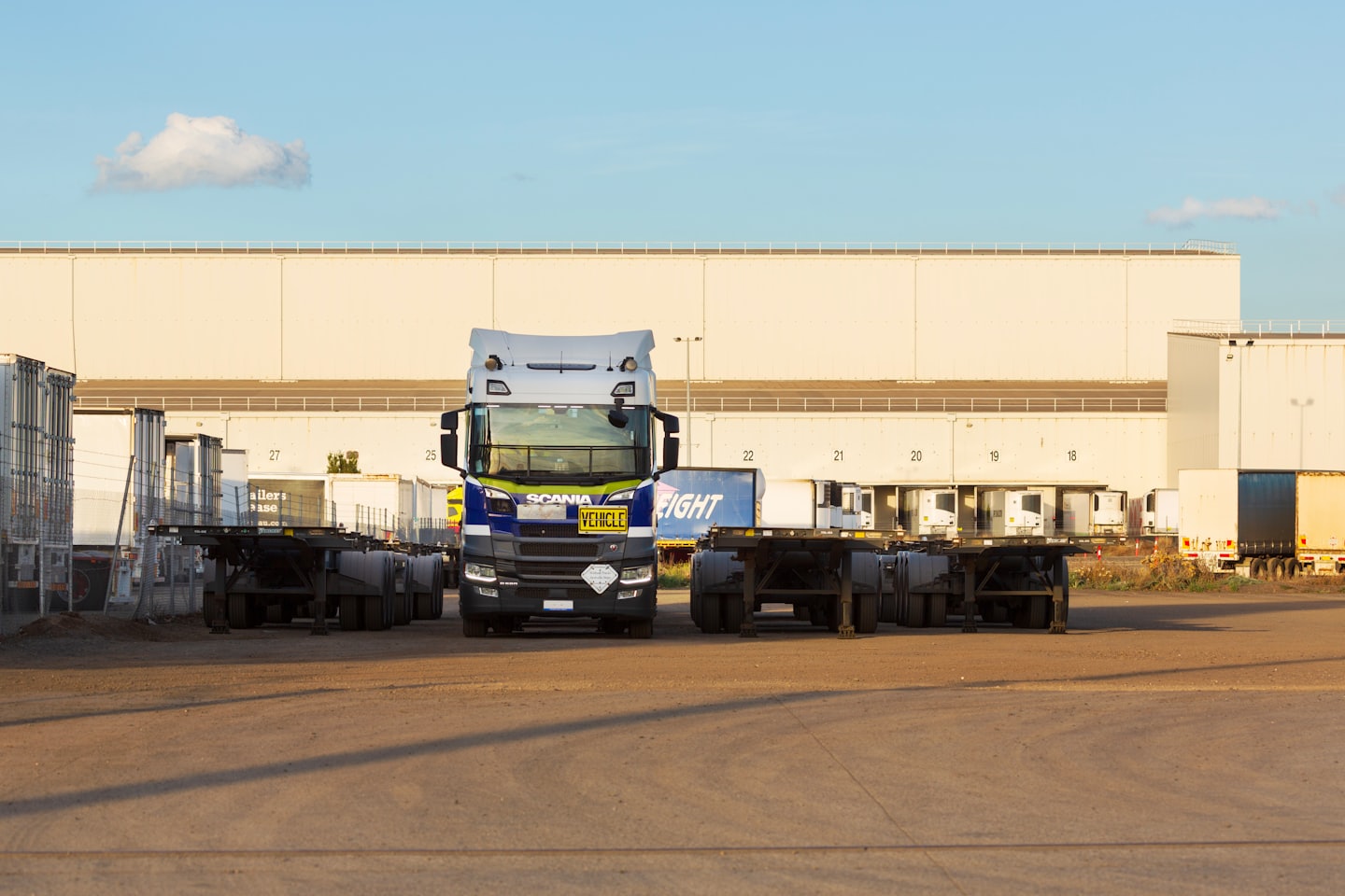 Blue and white Scania semi-truck parked in a logistics yard.