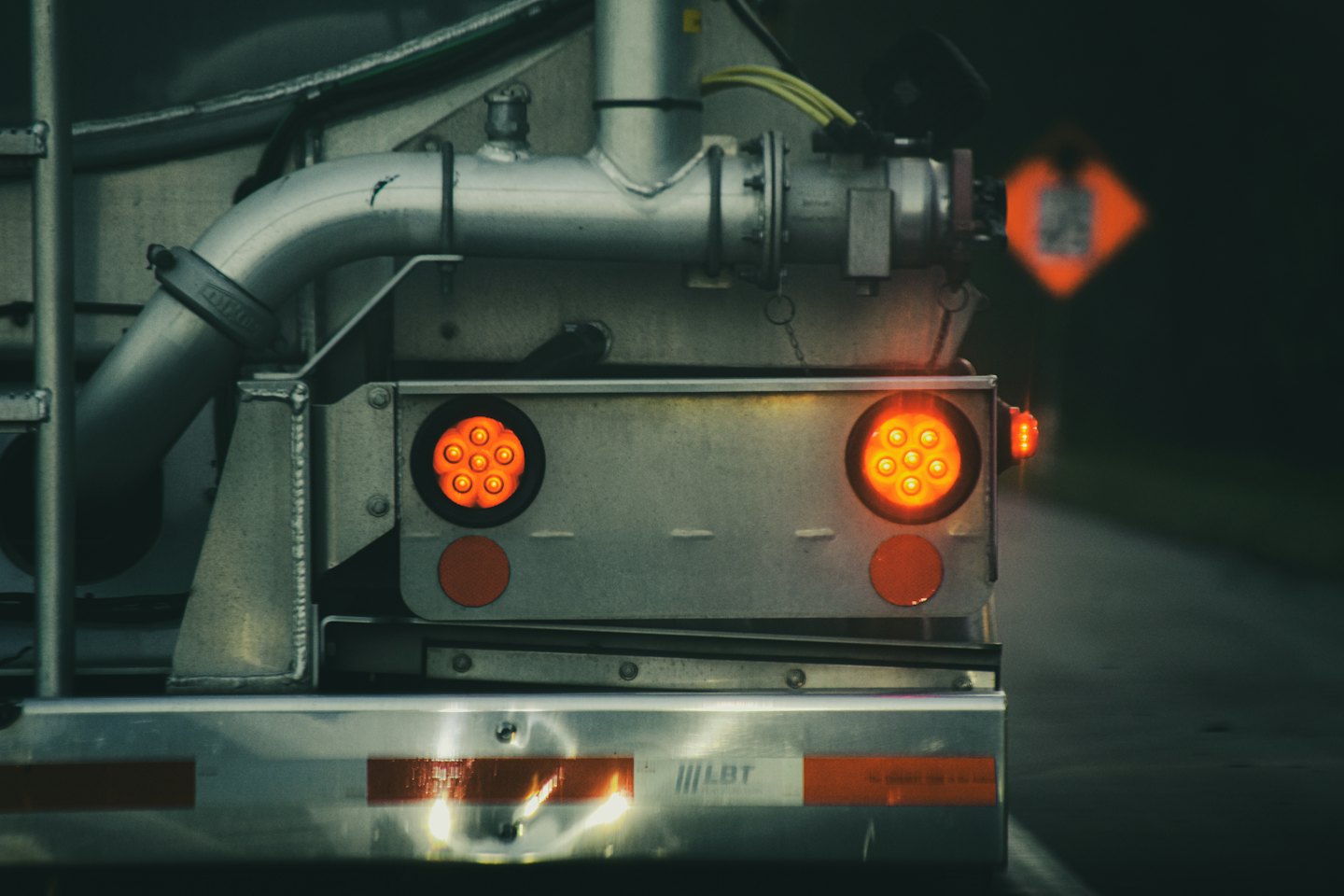 Rear of a tanker truck with illuminated orange taillights.