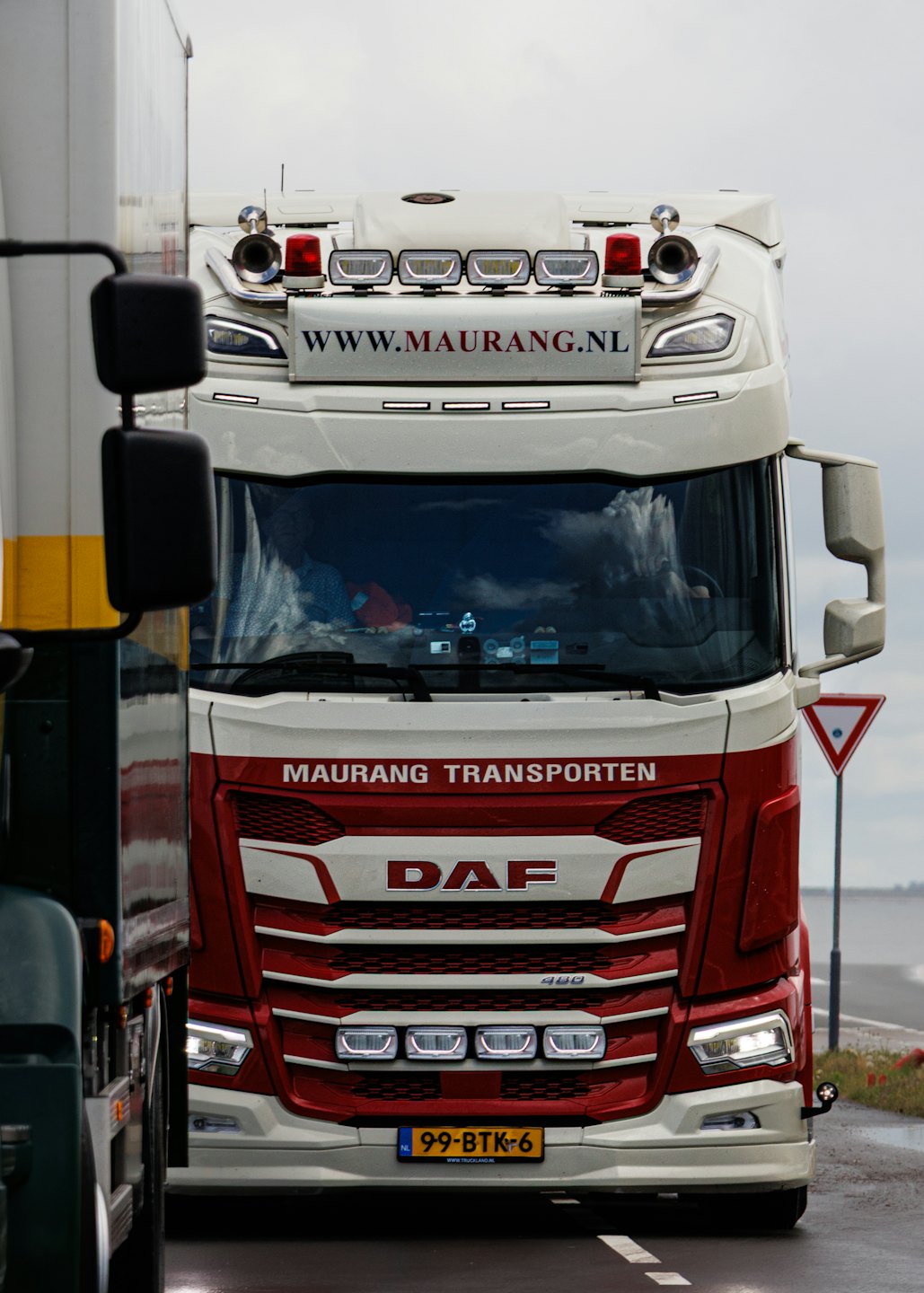 Red and white semi truck parked on a wet road.