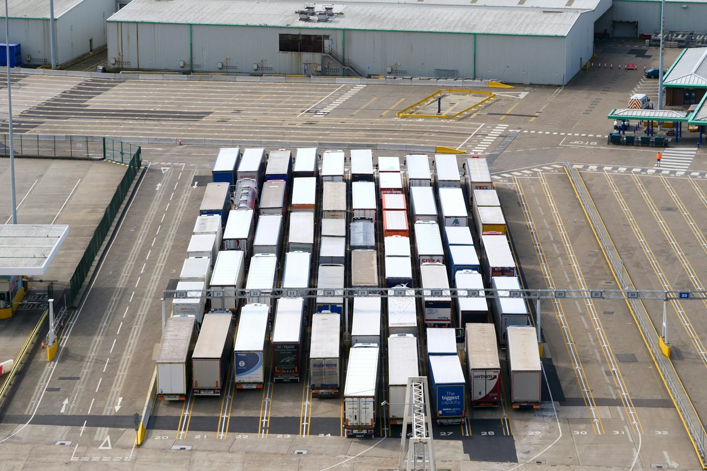 Semi-trailer trucks parked in rows at a logistics terminal.